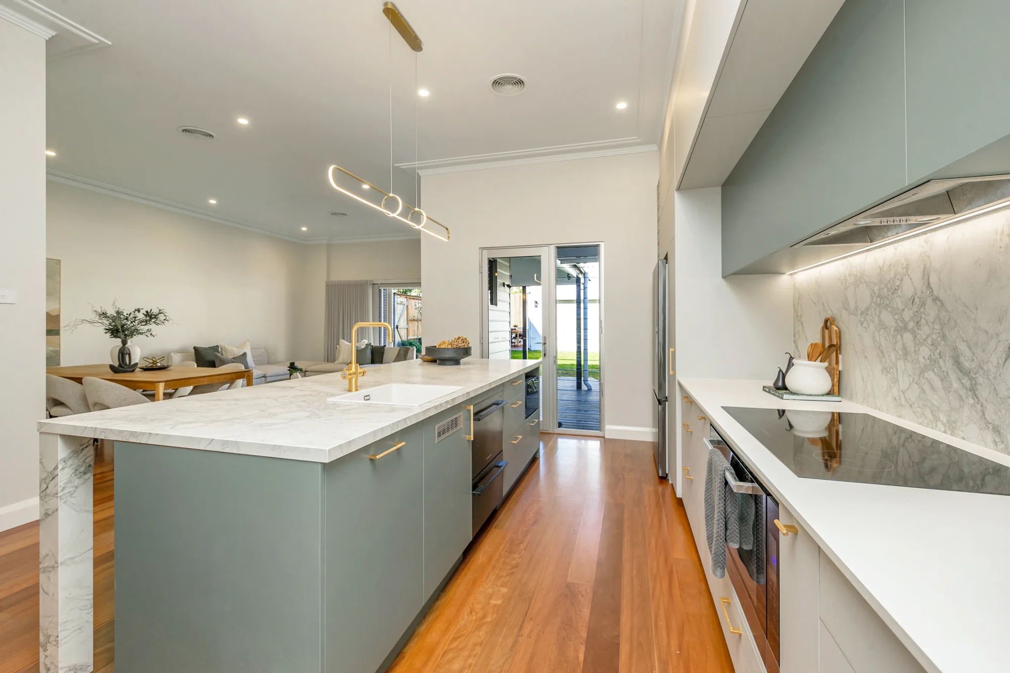 Sage green kitchen with Calacatta-look stone island and splashback